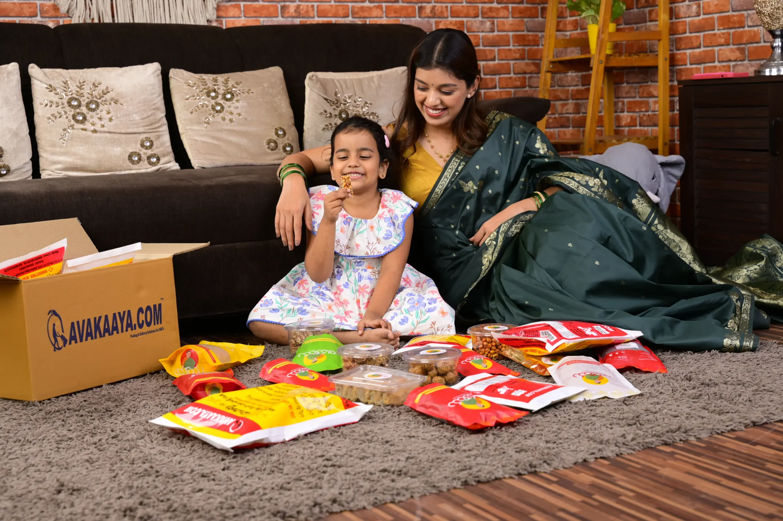 Mother and daughter happily unboxing AVAKAAYA.COM snacks at home, showcasing reliable door to door parcel services with care.