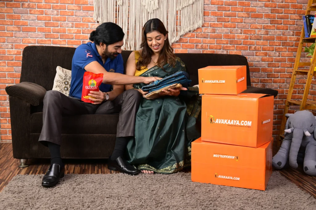 Couple receiving parcels at home with AVAKAAYA.COM boxes, showcasing best logistics services and reliable courier services.