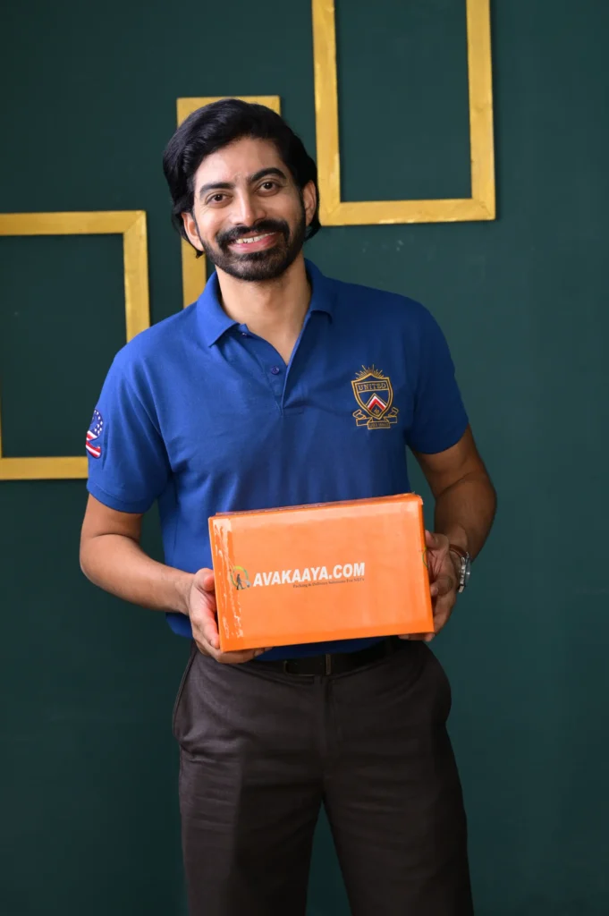 Smiling man in blue polo shirt holding Avakaaya.com box, representing reliable delivery from a trusted logistics company.
