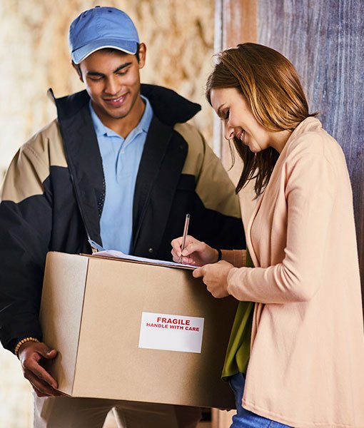 Smiling woman signs for a fragile package from courier at door, showcasing professional parcel delivery services.
